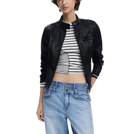 Woman in a black leather jacket, striped crop top, and blue jeans showcasing Desigual style