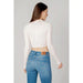 Woman in cropped white sweater and blue jeans from Tommy Hilfiger collection, back view