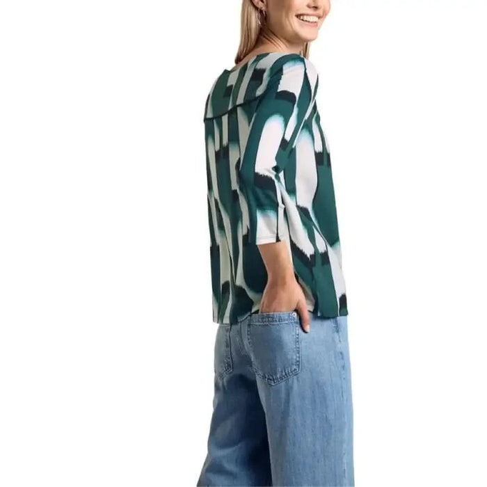 Woman in green and white patterned blouse by Street One, paired with blue jeans