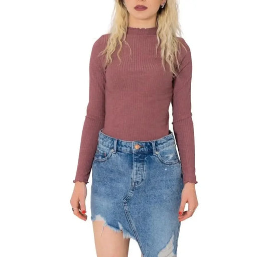 Woman in mauve ribbed top and distressed denim skirt, blonde hair, Only Women Knitwear