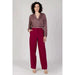 Woman in patterned blouse and burgundy trousers from Vila Clothes against light background