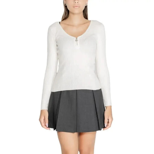 Woman in white long-sleeved top and dark pleated miniskirt from Morgan De Toi Knitwear