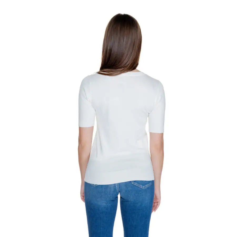 Woman in Guess white short-sleeved top and blue jeans, viewed from behind