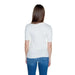 Woman in Guess white short-sleeved top and blue jeans, viewed from behind