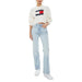 Woman wearing white Tommy Jeans sweatshirt and light blue jeans from Tommy Hilfiger