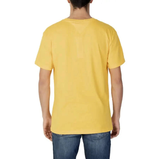 Yellow short-sleeved Tommy Hilfiger t-shirt worn by a person facing away from the camera